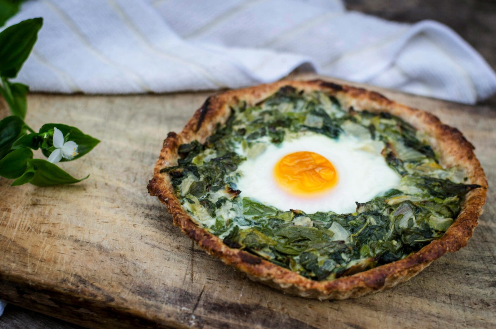 Delicious homemade spinach and egg tart elegantly presented on rustic wooden surface.