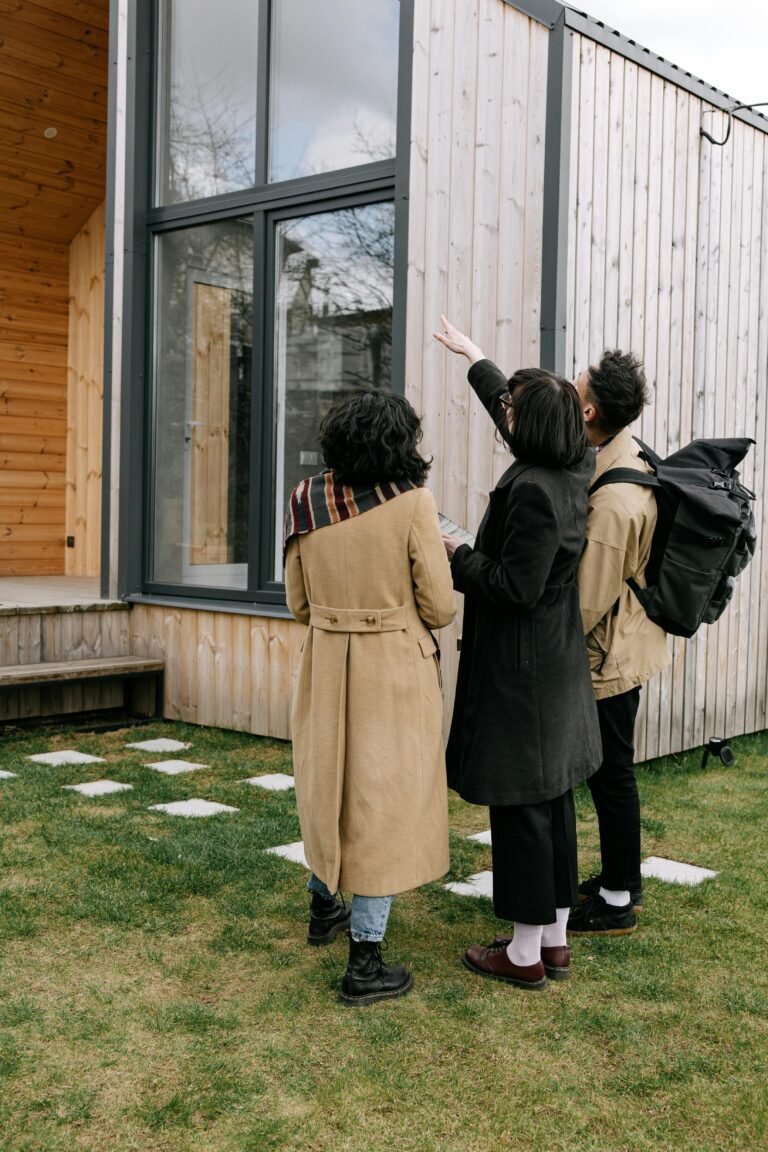 A group of adults inspecting a modern wooden house exterior with a real estate agent.